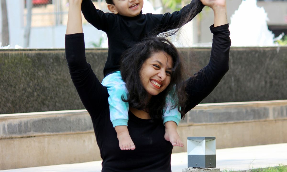 A mother and child laughing while playing together in a green park.