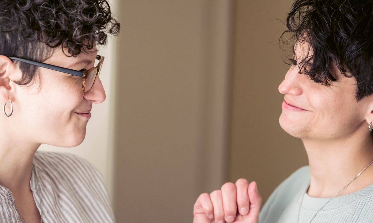 Two friends smiling and talking together in a bright home.