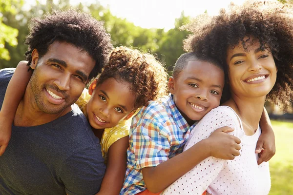 A family of four smiling together outside