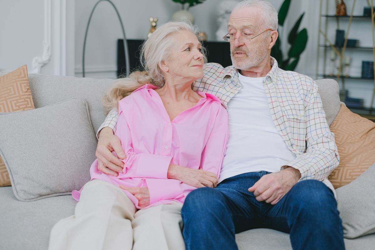 An older couple embracing on a comfortable living-room sofa.