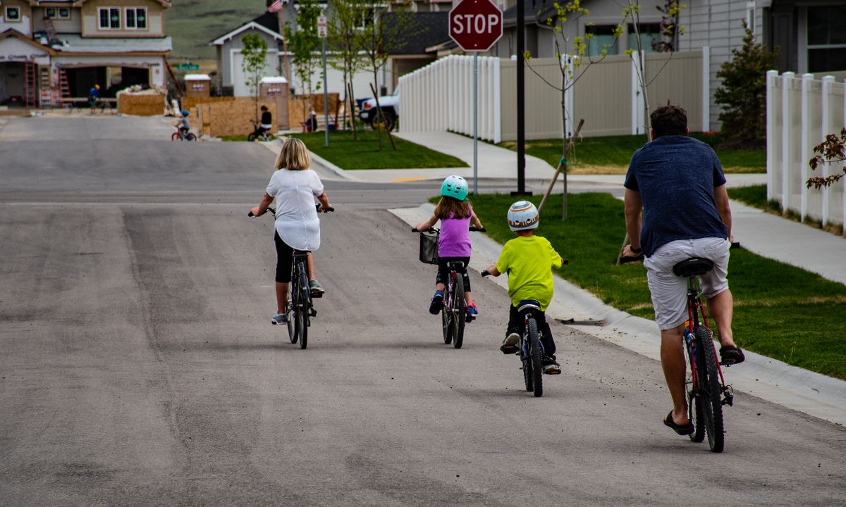 A family wearing helmets while bicycling together on a neighborhood street.