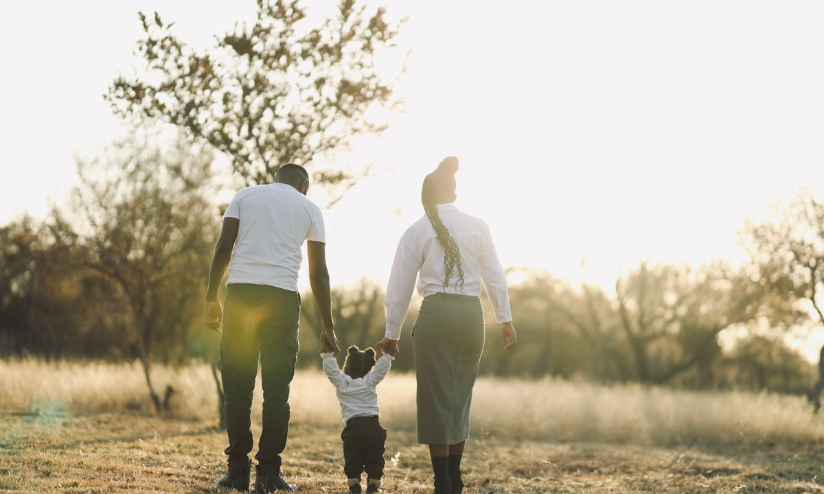 A family walking through a field together in warm sunlight.